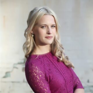 A head and shoulders photo of Holly Green, People & Culture Manager, wearing a pink top and looking into the camera