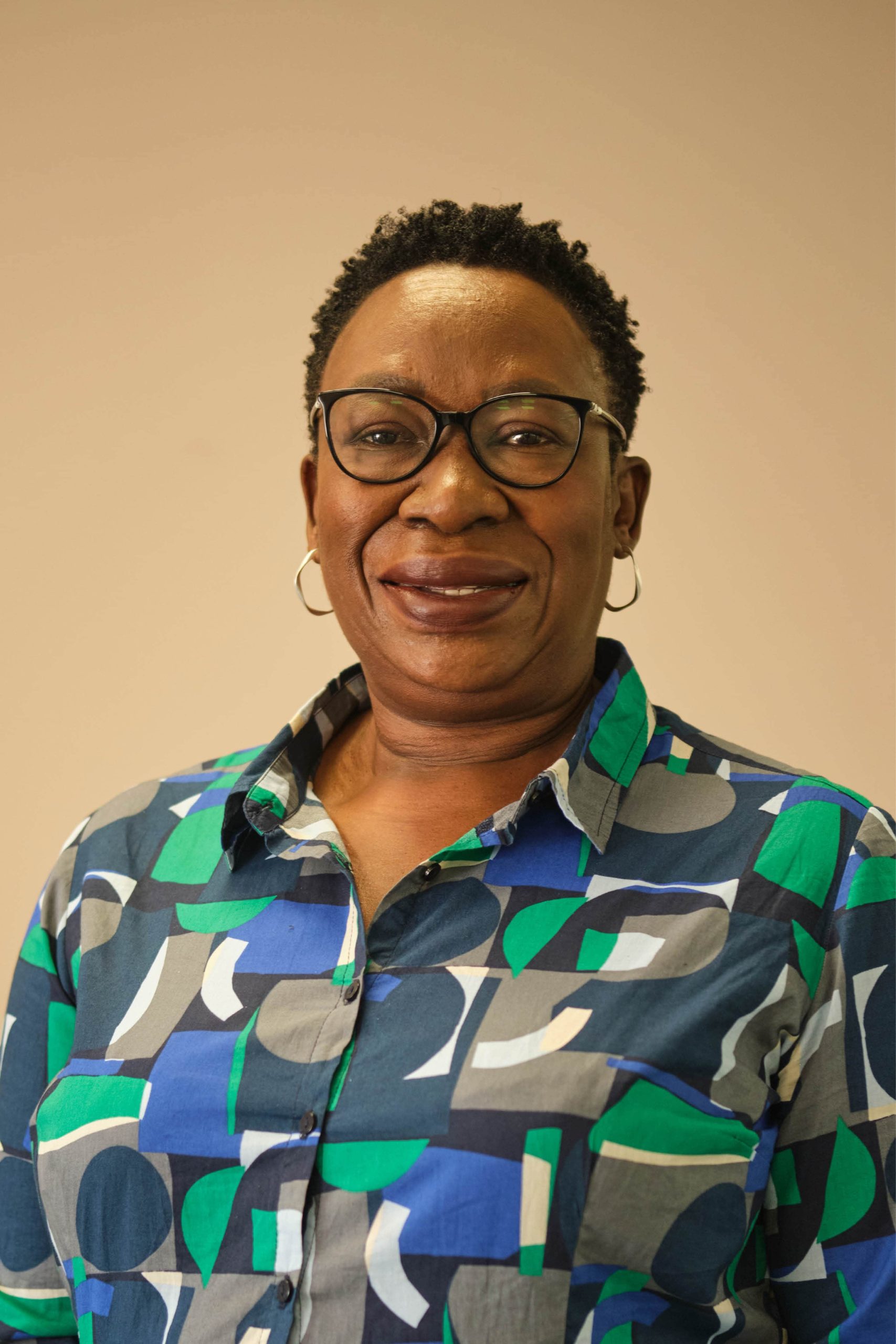 The image shows a person wearing glasses and a colorful shirt with a geometric pattern. The background is plain.